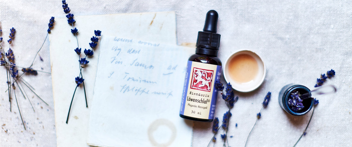 Fläschchen Löwenschlaf-Massageöl zwischen Lavendelblüten, handschriftlicher Notiz und Tinte