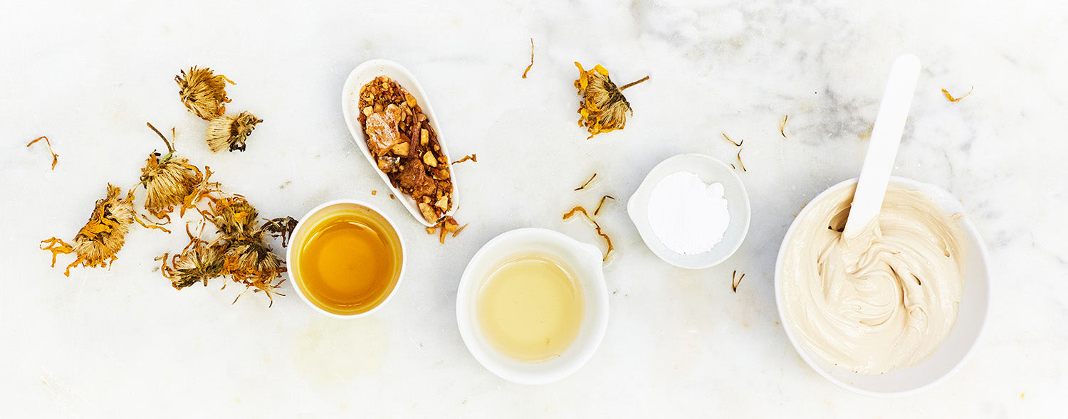 Naturkosmetische Zutaten wie getrocknete Blüten, Harze, Pflanzenöle, Pulver und eine angerührte Creme in einer Schale – symbolisch für die handgemachte Herstellung von Naturcremes.