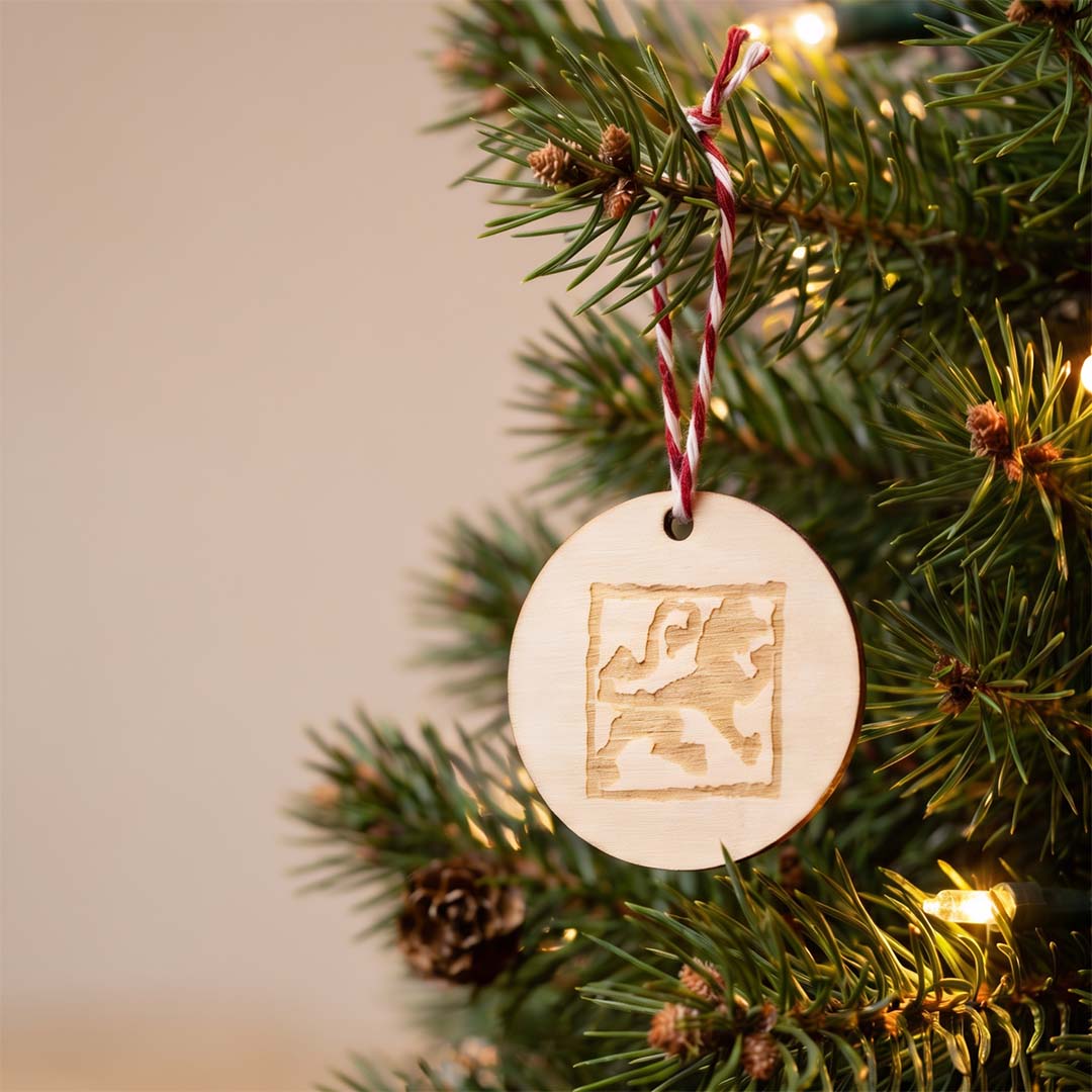 Duftanhänger Rund aus Holz mit Löwen-Manufaktur Logo Löwen in einer Tanne hängend, weihnachtliche Stimmung.