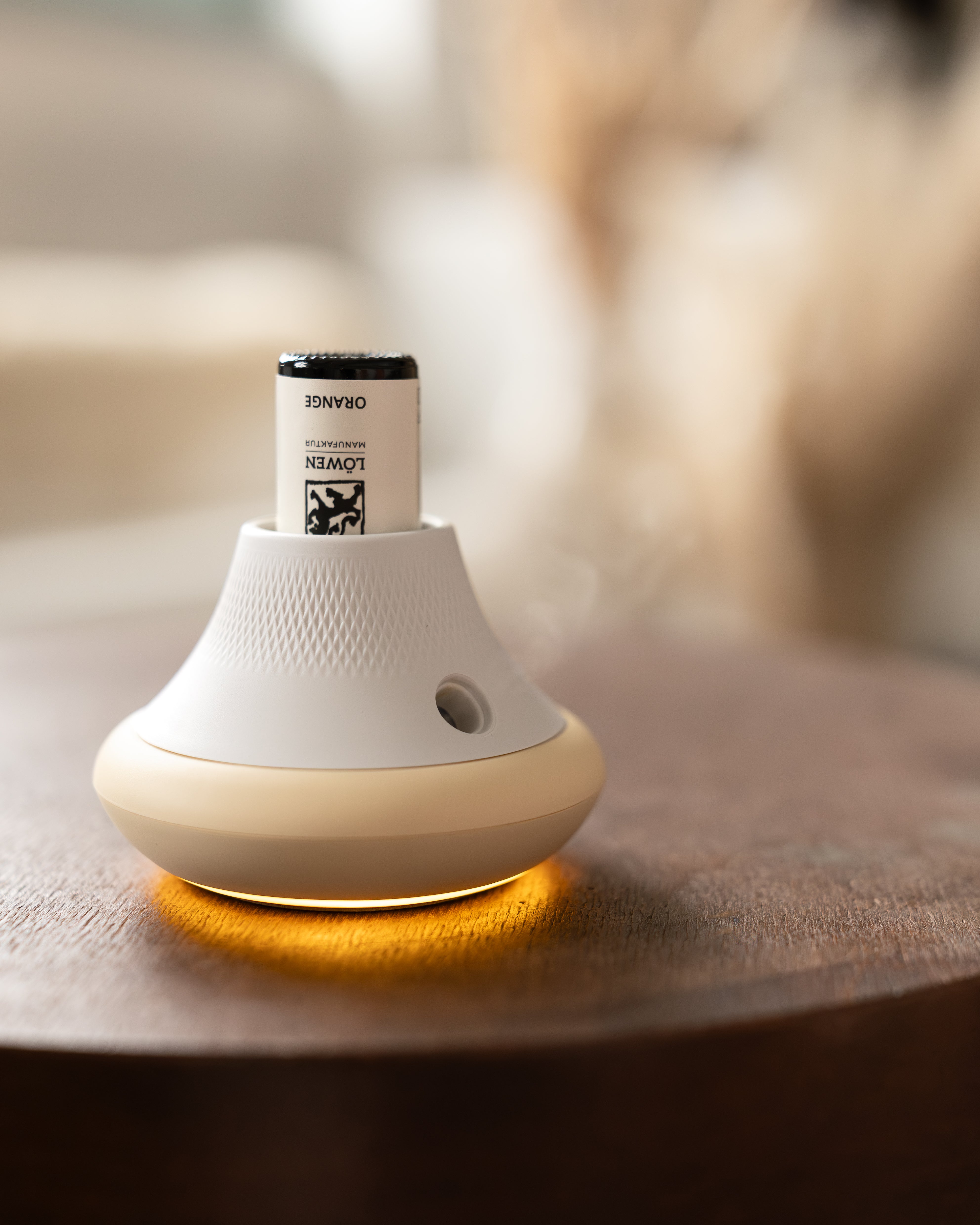 Modernes Duftgerät mit eingesetztem ätherischen Orangenöl von Löwen-Manufaktur, leuchtend aktiviert auf einem Holztisch – sanfte Lichtwirkung und dezente Verneblung im Einsatz.